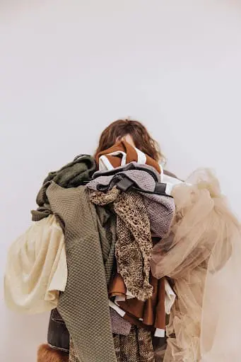 A person standing and holding messy clothes, representing the common struggle of wardrobe organisation for busy families.